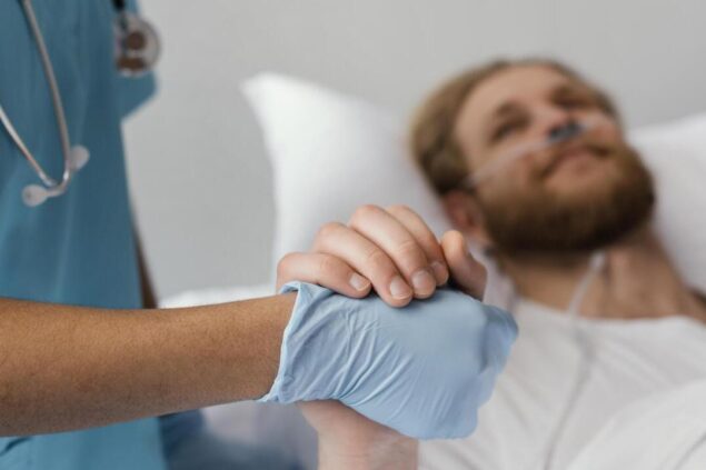 Profissional de saúde segurando a mão de um paciente internado em um leito hospitalar, transmitindo apoio e cuidado durante o tempo de internação.